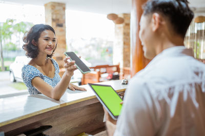 Side view of young woman using mobile phone while sitting in cafe