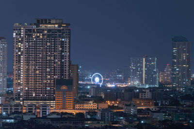 Illuminated buildings in city against sky at night