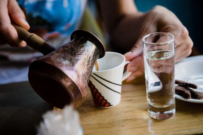 Midsection of man pouring drink on table