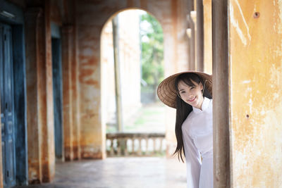 Portrait of woman standing by window in building