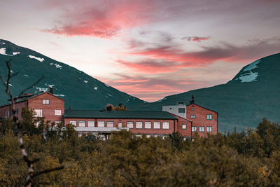 Houses by buildings against sky during sunset