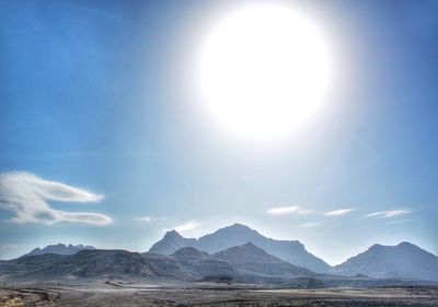 Scenic view of large bright sun over mountains