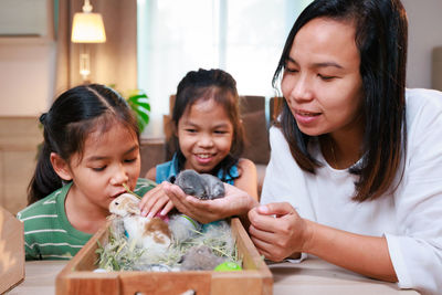 Mother and daughters holding baby rabbit