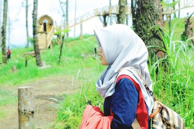 Side view of woman sitting on land