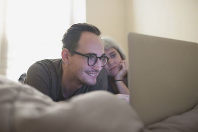 Young couple lying in bed looking at a laptop