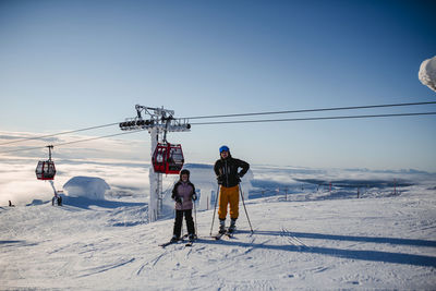 Rear view of people skiing on snowcapped mountain against sky