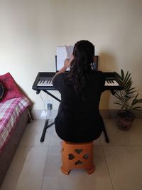 Rear view of woman using phone at home