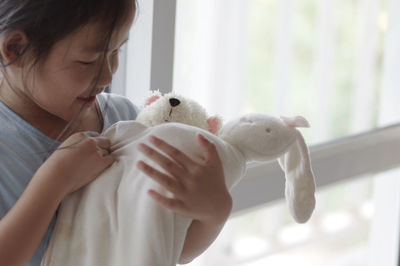 Cute girl playing with teddy bear at home