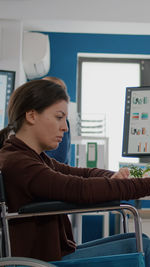 Side view of woman looking through window