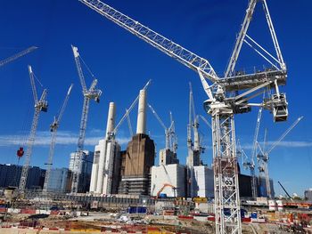 Low angle view of cranes against blue sky