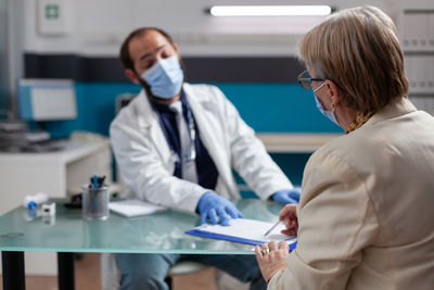 Doctor wearing mask getting customer sign in hospital