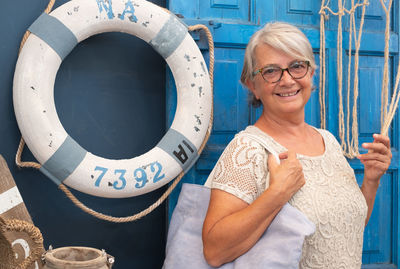 Portrait of smiling senior woman standing against blue door