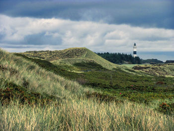 Lighthouse on field against sky