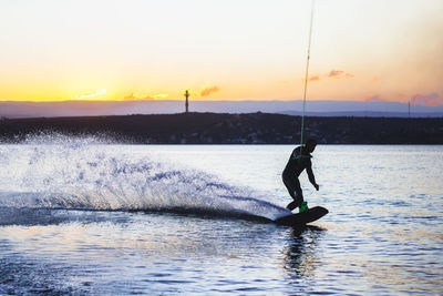 Wakeboarding man against sunset