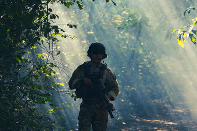 Full length of man standing by tree trunk