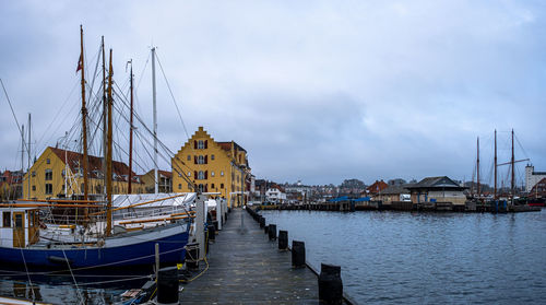 Sailboats moored at harbor against sky