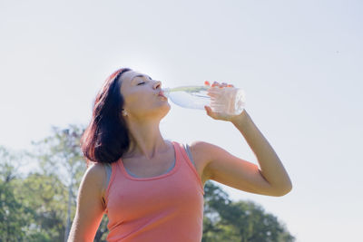 Midsection of woman drinking drink against sky