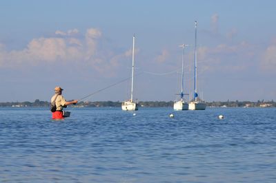 Rear view of a man fishing at calm sea