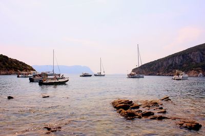 Sailboats on sea against clear sky