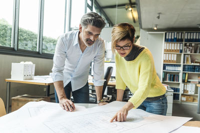 Male and female architects discussing ground plan in office