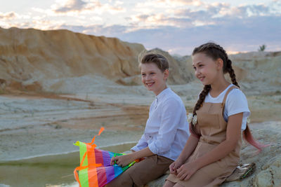Portrait of smiling friends sitting on mountain