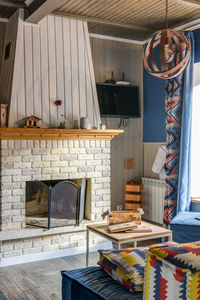 Stone fireplace in a country house with a multi-colored ethno sofa