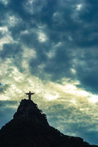 Low angle view of silhouette cross on mountain against sky