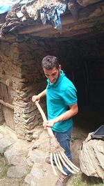 Full length of man holding work tool while standing at old ruin