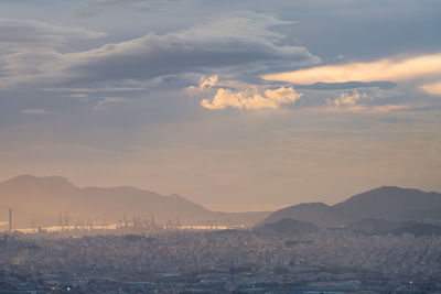 Aerial view of city by sea against sky during sunset