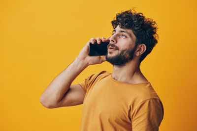 Side view of young man photographing against yellow background