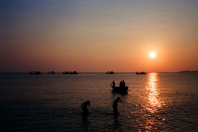 Silhouette people on beach against clear sky during sunset