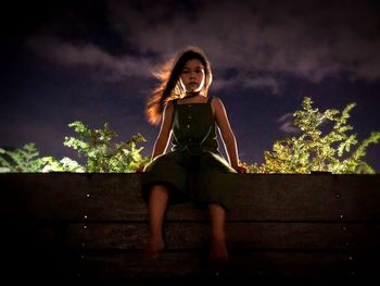 Full length portrait of woman sitting against tree