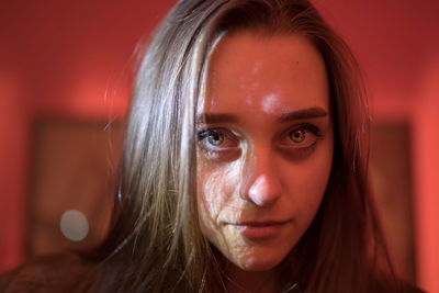 Close-up portrait of young woman in illuminated room