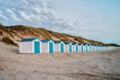 Deck chairs on beach against sky