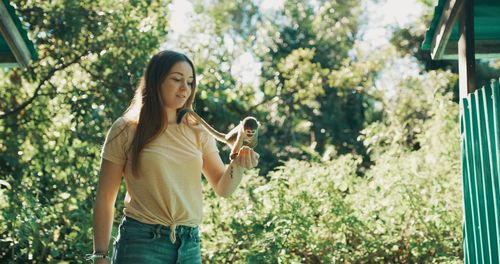 Full length of young woman standing against plants