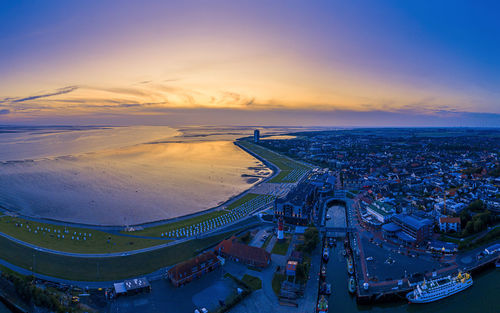High angle view of sea by buildings against sky during sunset