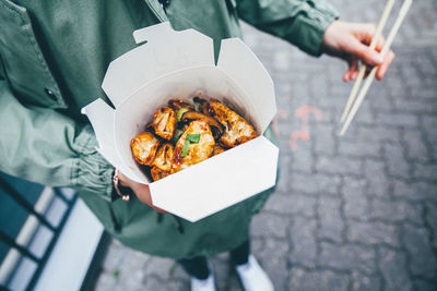 Midsection of person holding street food on sidewalk