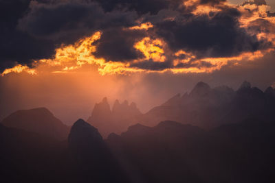 Scenic view of silhouette mountains against orange sky