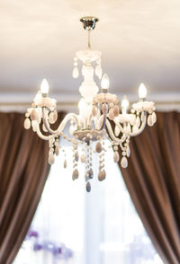 Low angle view of illuminated chandelier hanging from ceiling