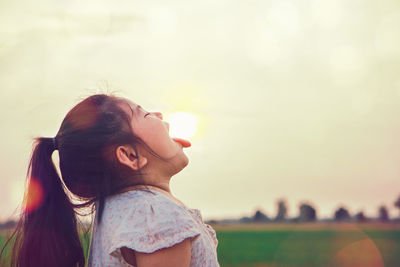 Side view of mother girl on field against sky during sunset