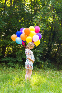Rear view of woman holding balloons on field