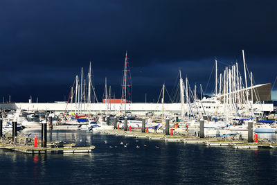 Sailboats moored on harbor against sky