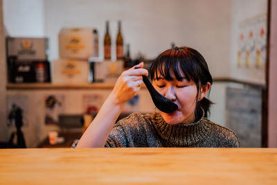 Portrait of young woman using mobile phone in restaurant