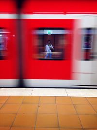 Reflection of person on red train window at subway station