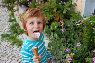 The blond boy shows his tongue stained with ice cream.boy   while looking directly at the camera.