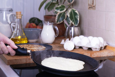 Housewife woman bakes pancakes for breakfast. home cooking pancakes in pan on glass-ceramic stove 