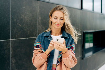 Portrait of young woman standing against wall