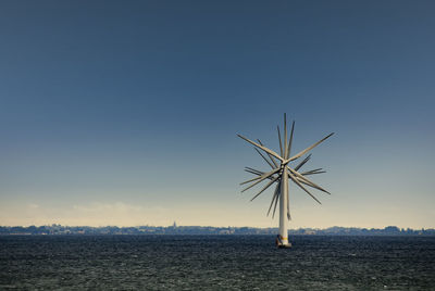 Windmills in sea against blue sky