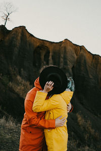 Rear view of man standing on mountain against sky