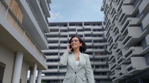 Caucasian successful businesswoman leader wearing suit walking in city and talking on mobile phone